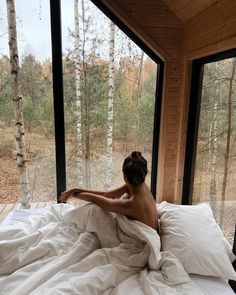 a naked woman sitting on top of a bed in a bedroom next to a window