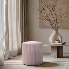 there is a pink stool next to a white vase