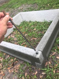 a man is holding a piece of metal in front of a cement box on the ground