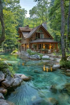 a log cabin sits on the edge of a river surrounded by rocks and greenery