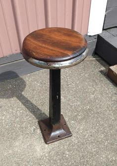 a wooden stool sitting on top of a cement floor next to a pink wall and door