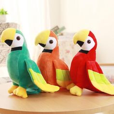 three stuffed parrots sitting on top of a wooden table