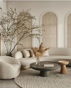 an elegant living room with white furniture and large round coffee table in front of the couch