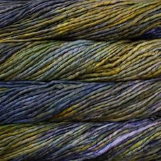 several skeins of yarn are stacked on top of each other in shades of blue, green and yellow