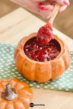 a person dipping jam into a pumpkin shaped bowl