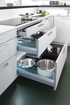 an open drawer in a kitchen with pots and pans