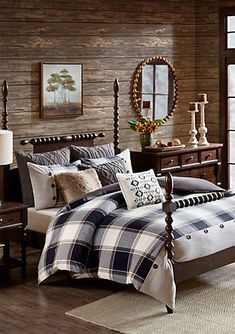 a bed with plaid comforter and pillows in a room next to a wooden headboard