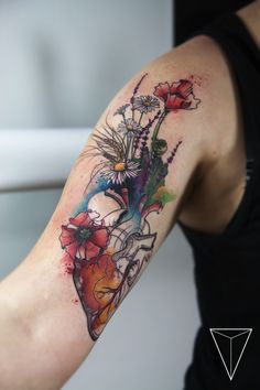 a woman's arm with flowers on it and a heart shaped tattoo design in the center