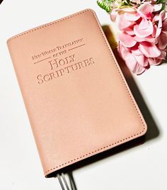 a pink book sitting on top of a white table next to a vase with flowers