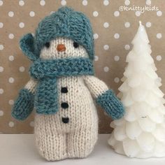 a knitted snowman next to a small christmas tree