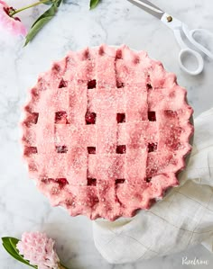 a strawberry pie with powdered sugar on top and pink flowers in the back ground