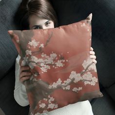 a woman is holding a pillow with flowers on it