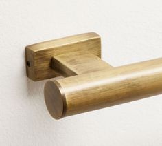 a close up of a brass colored handle on a white wall mounted toilet paper dispenser