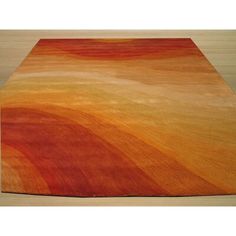 an orange, yellow and red rug on top of a wooden floor