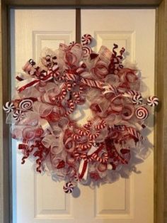 a wreath made out of candy canes is hanging on the front door to welcome guests