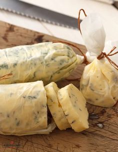 some food is wrapped in plastic and sitting on a cutting board next to a knife