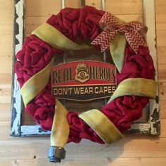 a red and yellow wreath hanging on the side of a door with ribbon around it