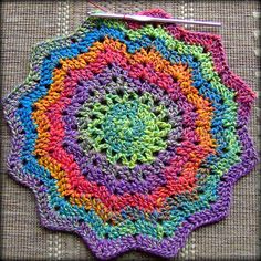 a crocheted doily with multicolored circles in the shape of a flower