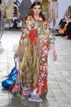 a woman is walking down the runway in a costume made out of balls and feathers