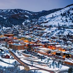 an aerial view of a town in the mountains at night with snow on the ground