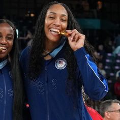 two women in blue jackets standing next to each other and eating food from their mouths