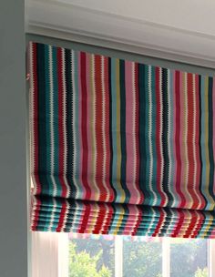 a multicolored striped roman blind hanging in front of a window