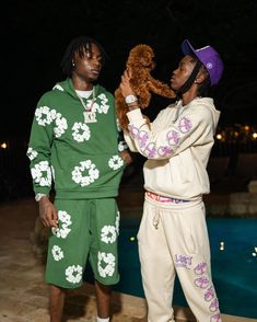 two men standing next to each other holding a teddy bear in front of a pool