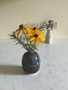 there is a vase with yellow flowers in it and an angel figurine next to it