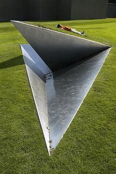 a large metal sculpture sitting on top of a lush green field