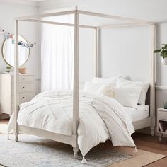 a bed with white linens and pillows in a room next to a window,