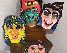 four masks are sitting on top of a wooden stand