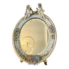 an ornate mirror with two cherubs on it's sides and flowers around the edges