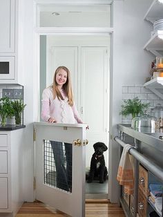 a woman standing at the door to her kitchen with a dog in it's kennel