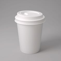 a white coffee cup sitting on top of a gray table next to a black object