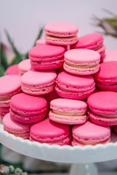 pink macaroons are stacked on a white plate