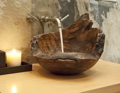 a wooden bowl shaped sink sitting on top of a counter next to a lit candle