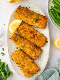 fish fillets on a plate with lemon wedges and green beans