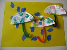 two paper fans on a yellow background with blue and green leaves attached to them,