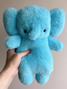 a person holding a blue stuffed animal in their hand