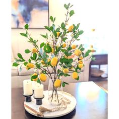 there is a vase with lemons and candles on the table