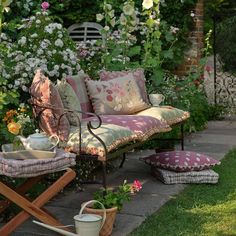 a garden with lots of flowers and plants on it's sides, including a bench