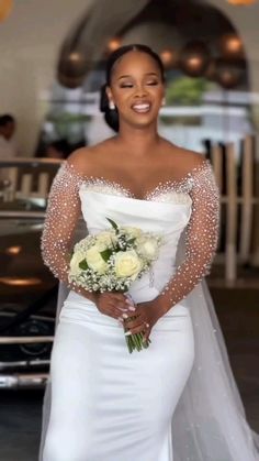 a woman in a wedding dress standing next to a black car and smiling at the camera