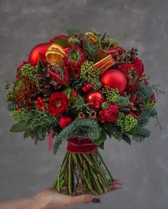 a bouquet of red flowers and greenery in someone's hand