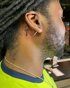 a man with dreadlocks and a cross tattoo on his ear