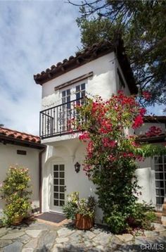 a white house with red flowers in the front yard