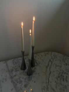 three candles sitting on top of a marble table