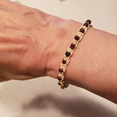 a woman's arm with a gold chain and garnets bracelet on it