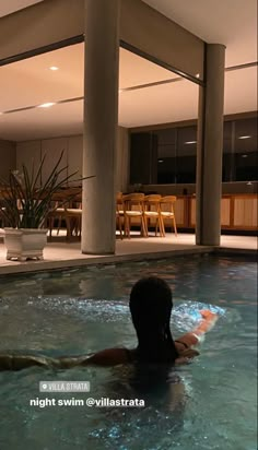 a woman is swimming in the pool at night