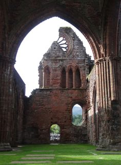 an old building with arches and grass in the foreground