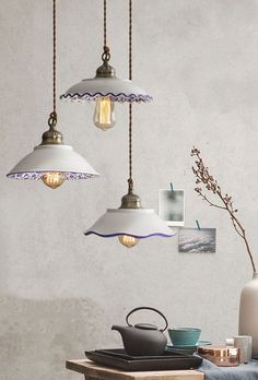 three pendant lights hanging over a table with teapots and cups on the table